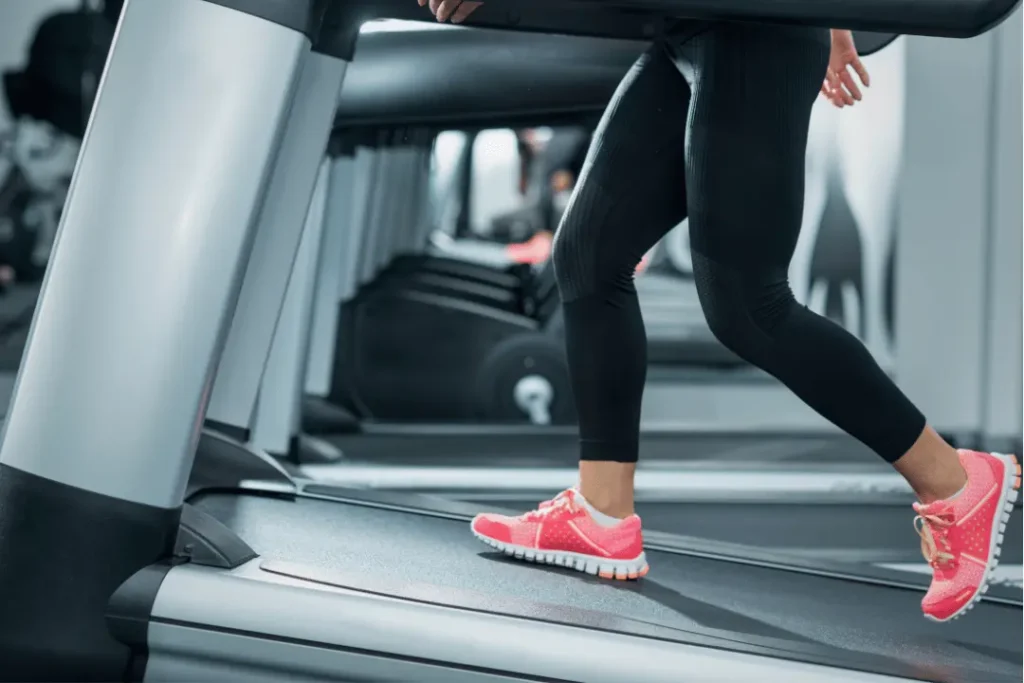 A woman walking on a treadmill with incline at the gym